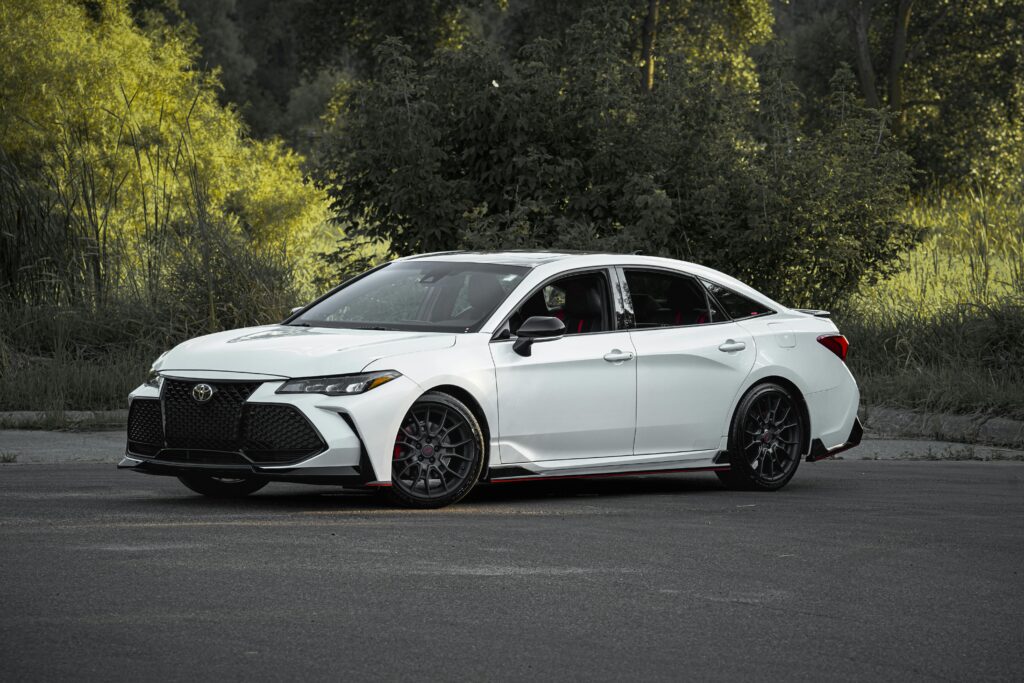 Stylish white sedan parked against a lush green background, perfect for automotive advertising.