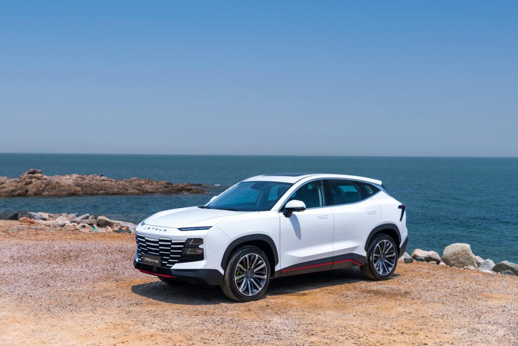 Elegant white SUV parked by the sea on a clear sunny day, perfect for coastal adventures.