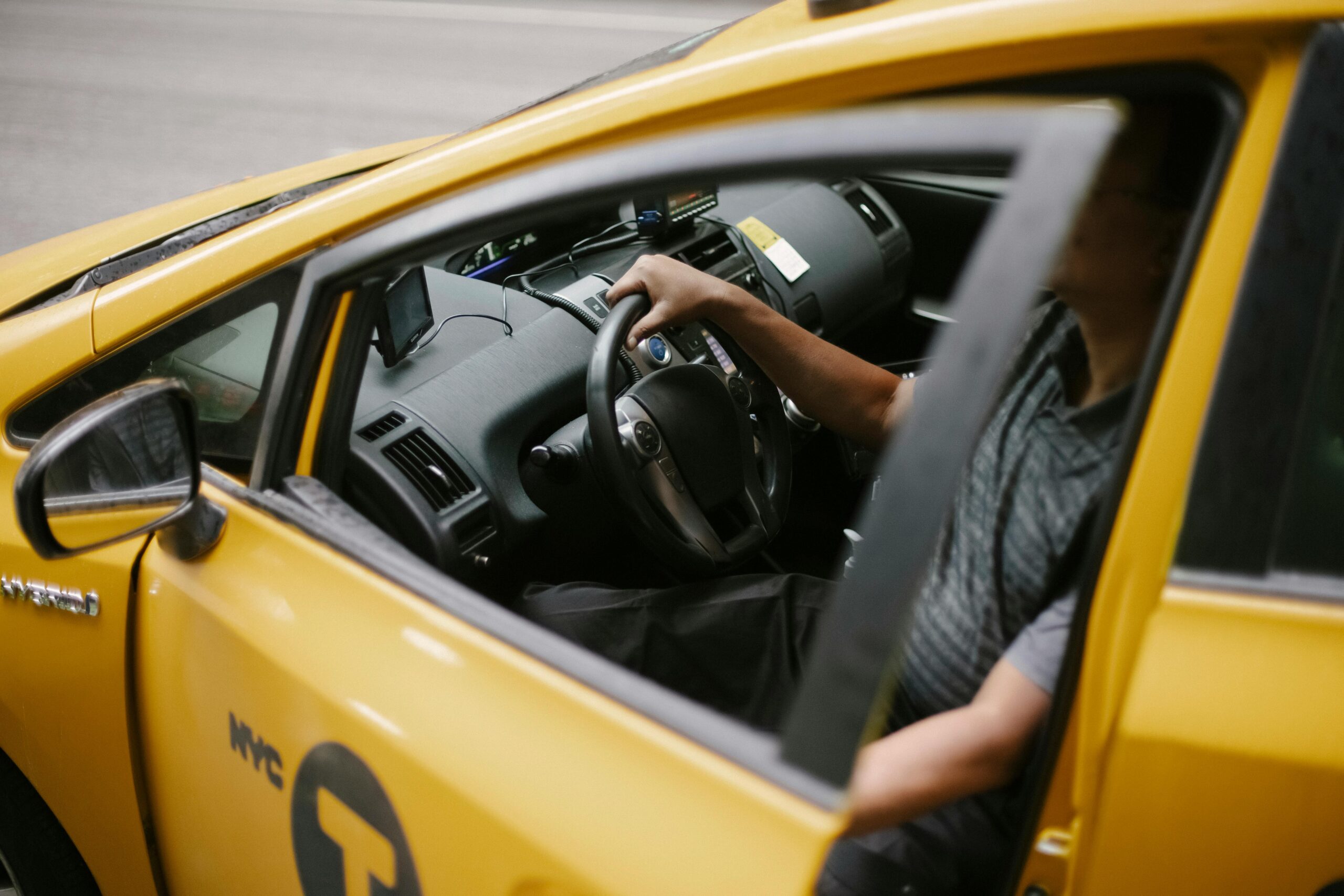 Home From above of anonymous man holding steering wheel and sitting in yellow car on road in daytime